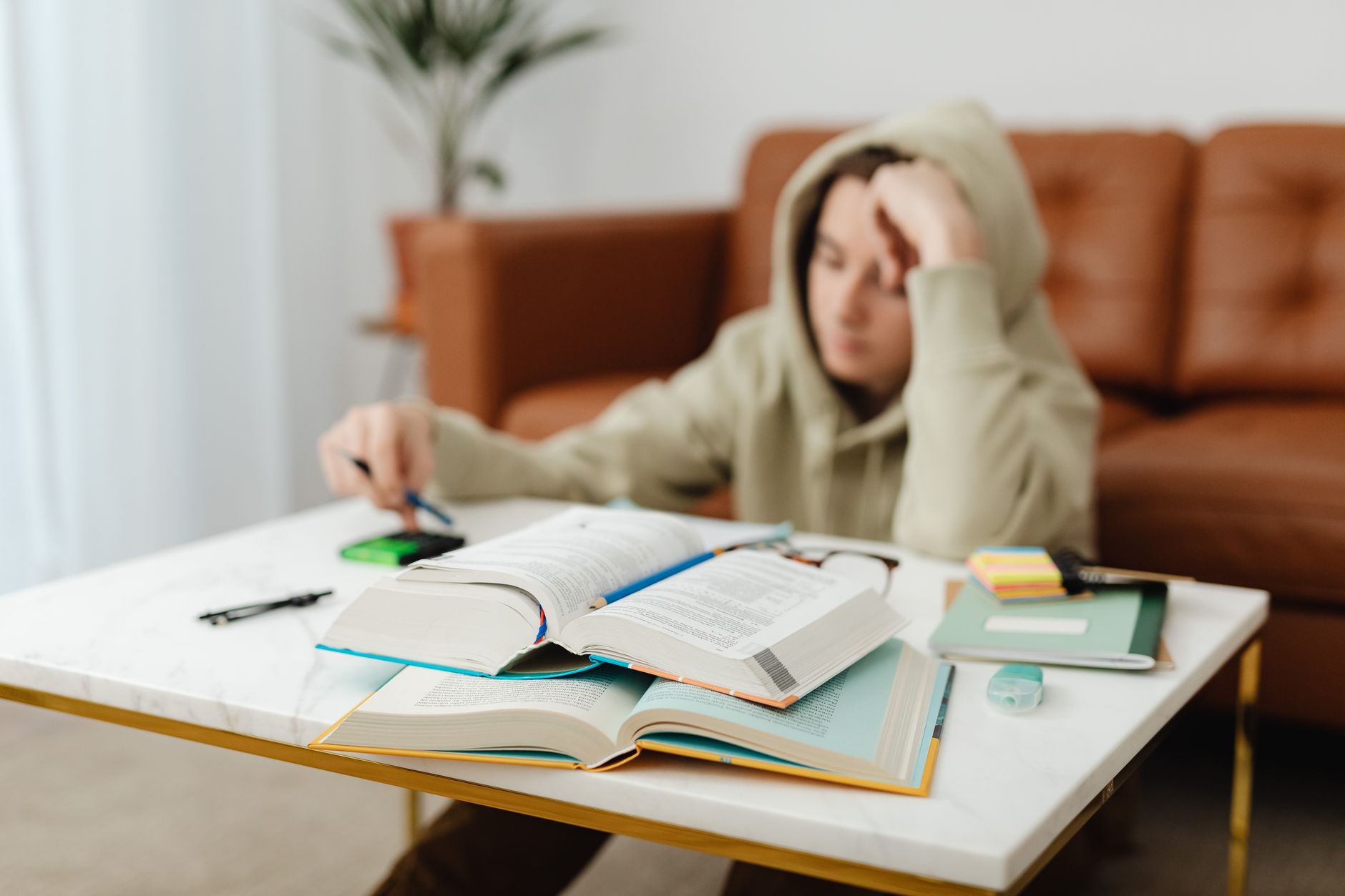 A teenager in a hoodie revising at a desk during hay fever season.